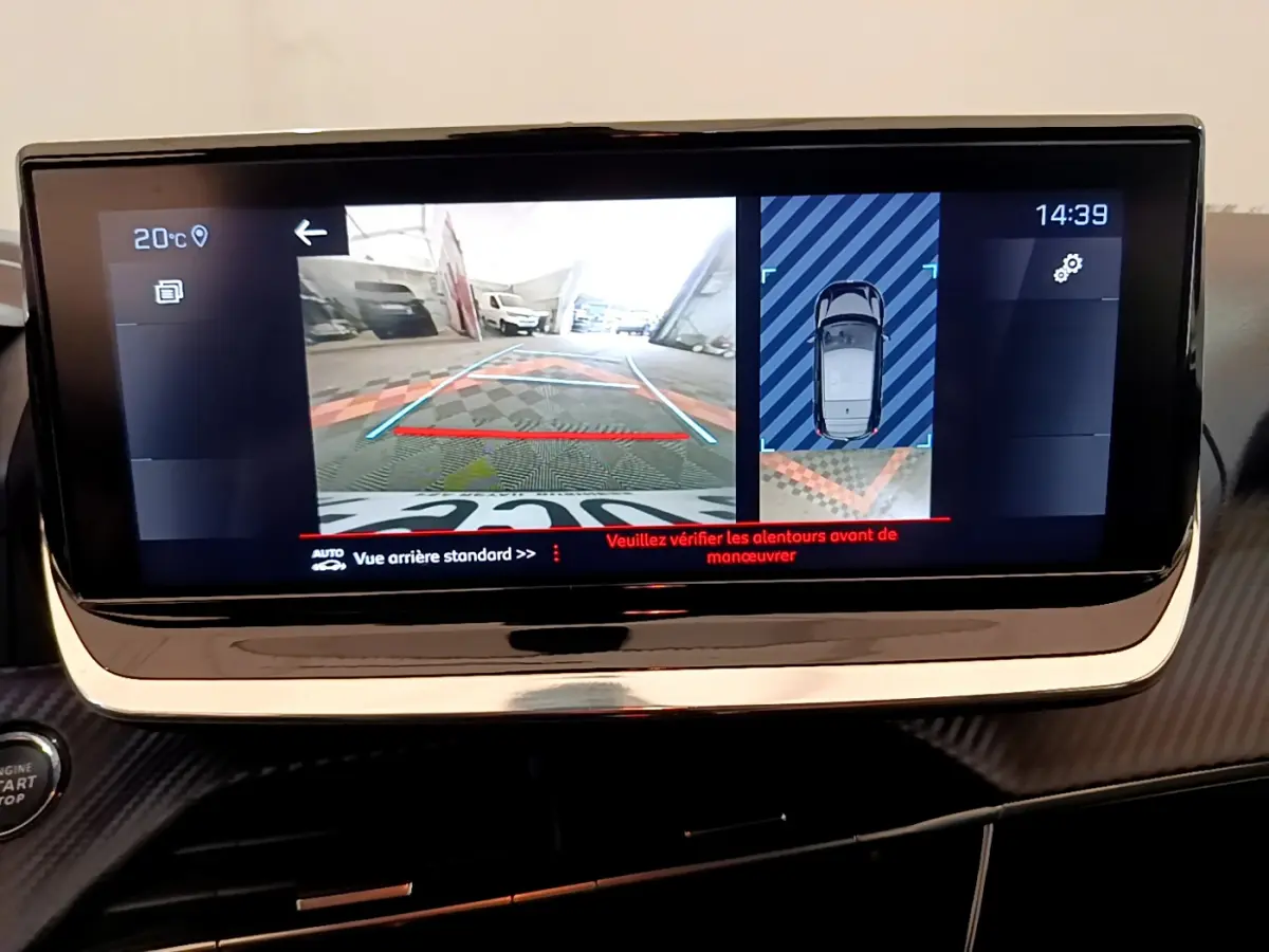Écran tactile central montrant la caméra de recul et l'aide au stationnement du Peugeot 208 blanc, vue intérieure avant.