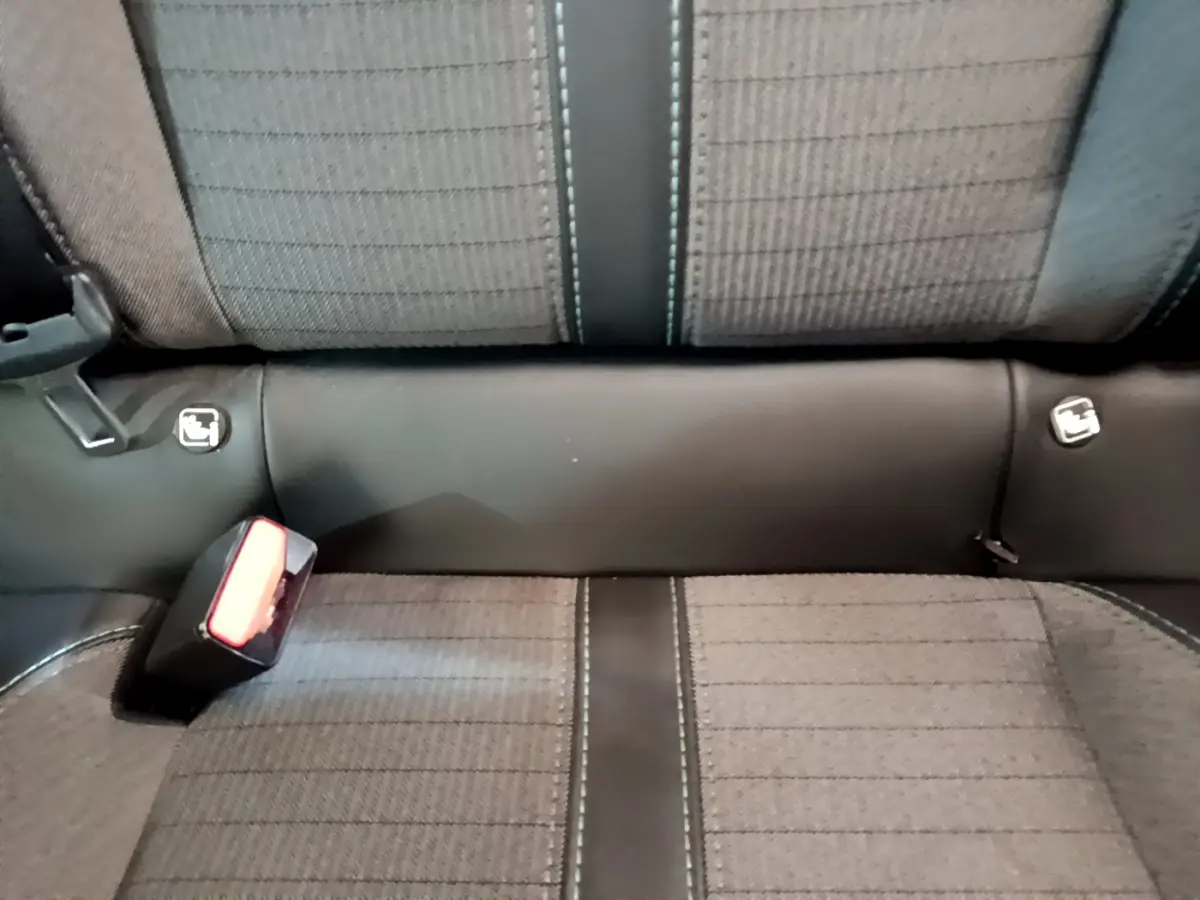 Gros plan sur la banquette arrière grise avec coutures contrastées et fixations Isofix visibles dans la Peugeot 208 blanche.