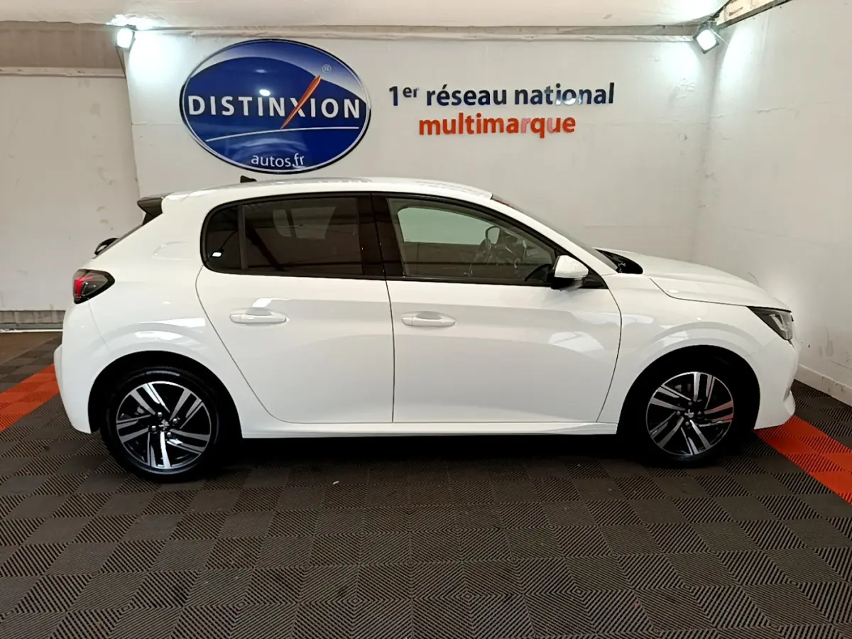 Profil côté gauche d'une Peugeot 208 blanche 2020, finition Allure Business, avec jantes alliage et vitres teintées.