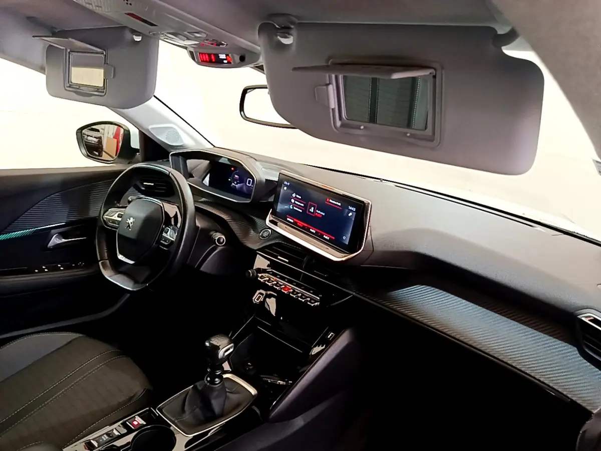 Vue intérieure côté conducteur de la Peugeot 208 blanche 2020, avec tableau de bord numérique et écran tactile central.