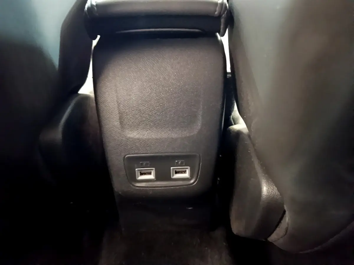 Vue rapprochée des ports USB arrière entre les sièges noirs d'une Peugeot 208 PureTech 100 S&S Allure Business 2020.
