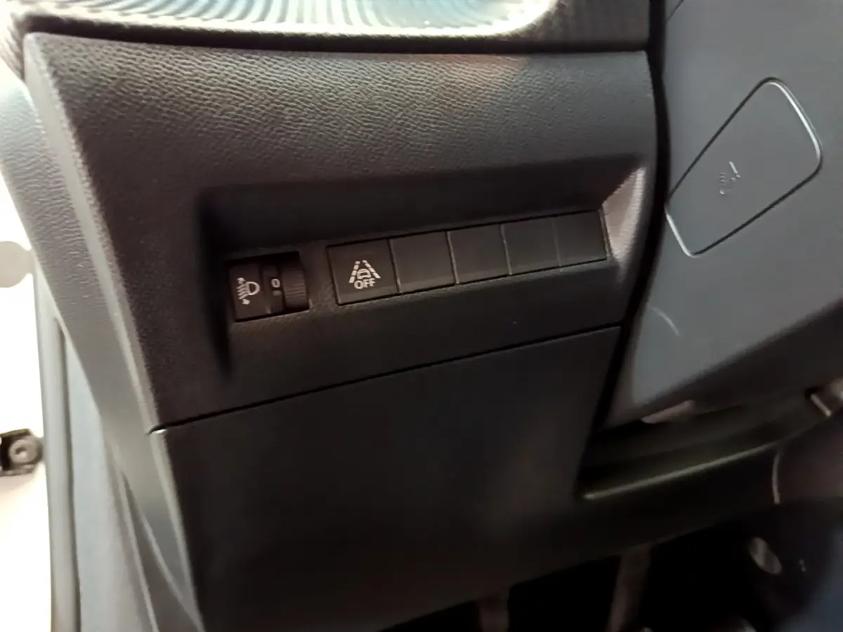 Détail des commandes de réglage des phares et d'activation de l'assistance au maintien de voie côté gauche sur Peugeot 208 blanc 2020.