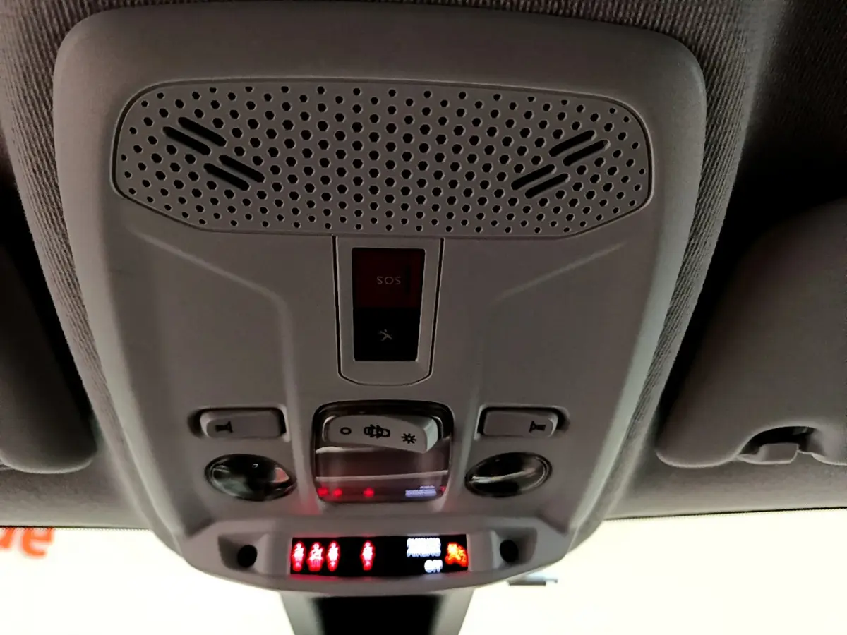 Vue en contre-plongée du plafonnier gris clair du Peugeot 208 PureTech 100 S&S Allure Business avec boutons SOS et éclairage intégré.