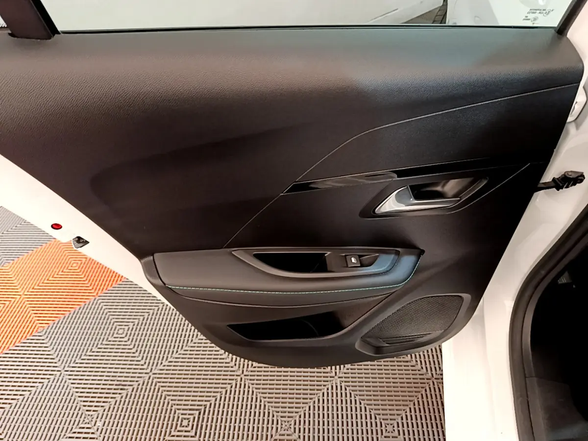 Gros plan sur la porte avant gauche noire de la Peugeot 208 blanche, avec poignée argentée et commande de vitre.