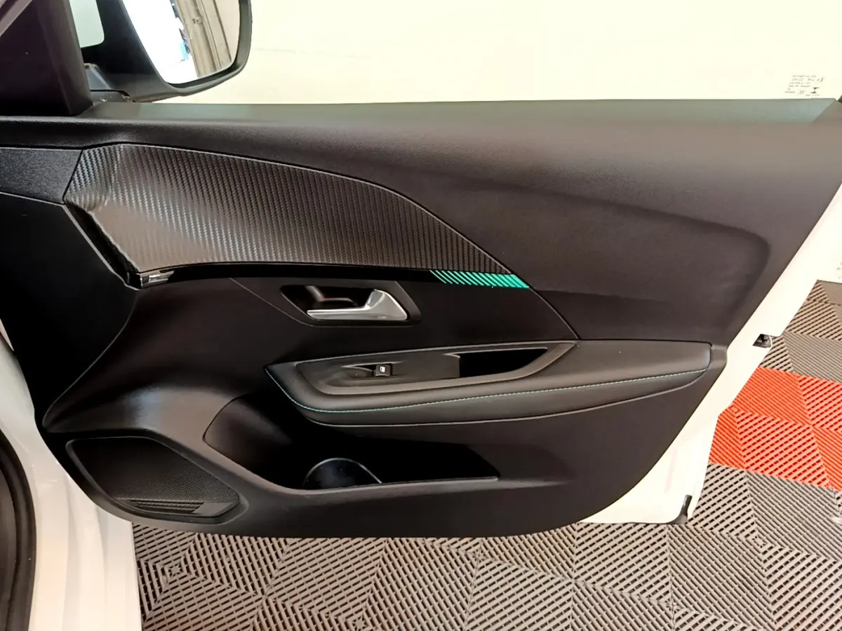 Vue intérieure de la porte côté gauche blanche d'une Peugeot 208 avec garniture noire et surpiqûres bleues.