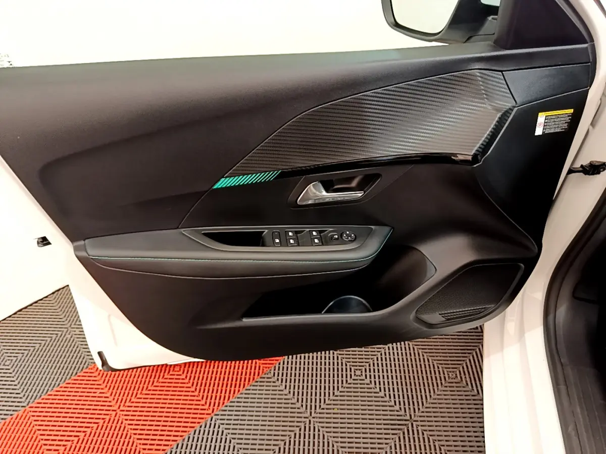 Vue rapprochée de la porte avant gauche blanche du Peugeot 208 2020, avec habillage noir et insert imitation carbone.