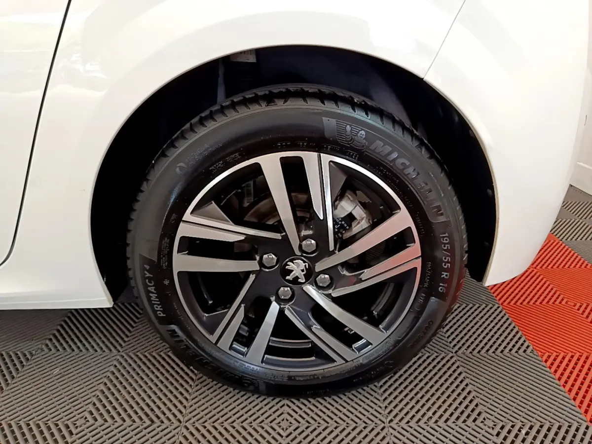 Gros plan sur la roue arrière droite de la Peugeot 208 blanche avec jante alliage noir et argentée.