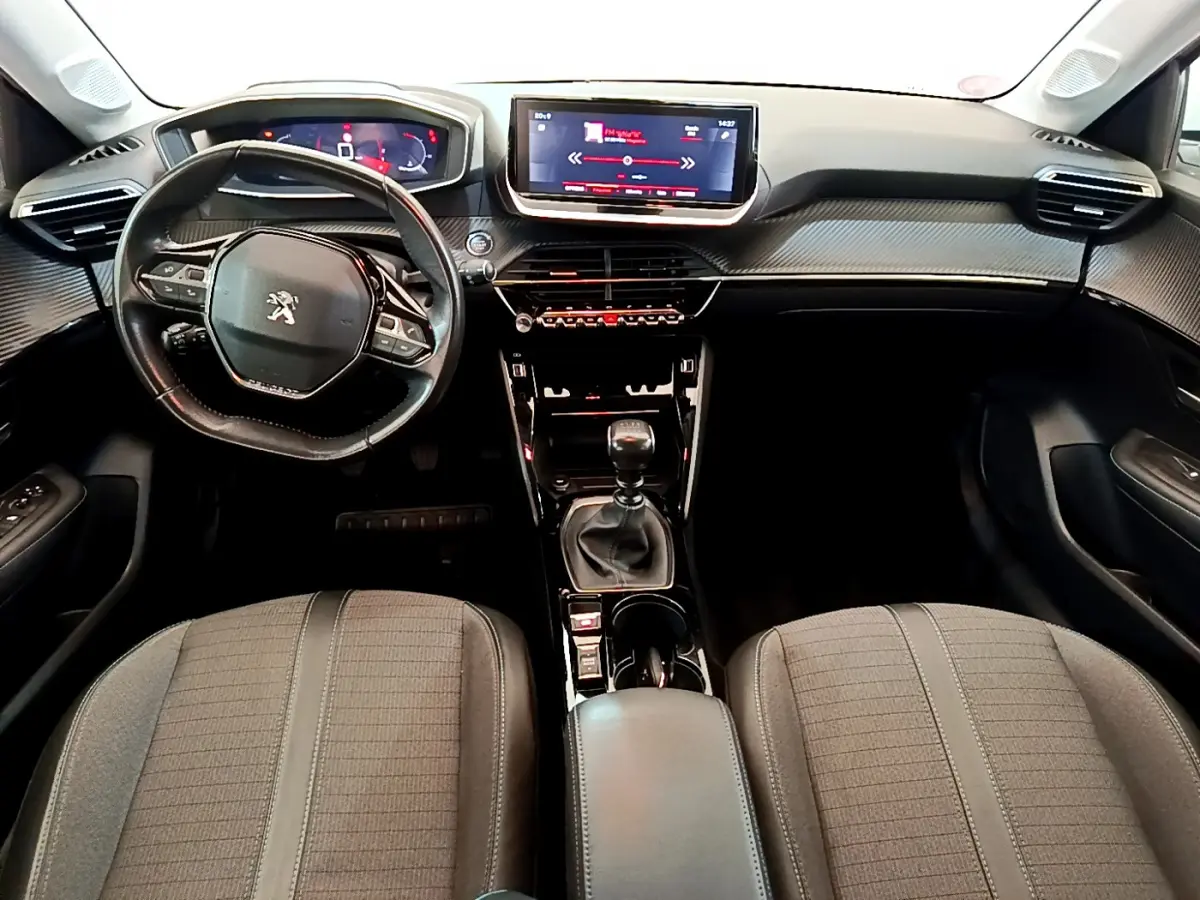 Intérieur de la Peugeot 208 PureTech 100 vue de face, tableau de bord noir avec écran tactile central et volant cuir.