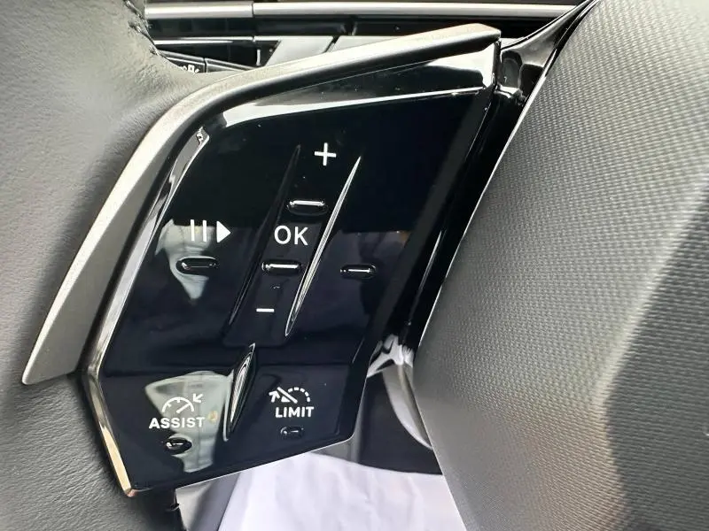 Gros plan sur les commandes au volant noir brillant du Peugeot 3008 gris Titane, avec boutons multifonctions et régulateur de vitesse.