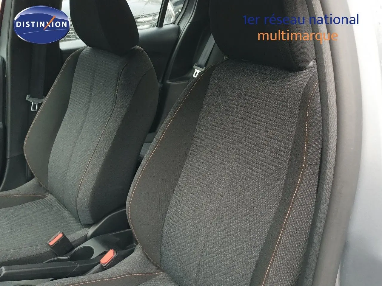 Gros plan sur les sièges avant en tissu noir avec surpiqûres orange d'une Peugeot 208 gris Artense, vue côté droit.