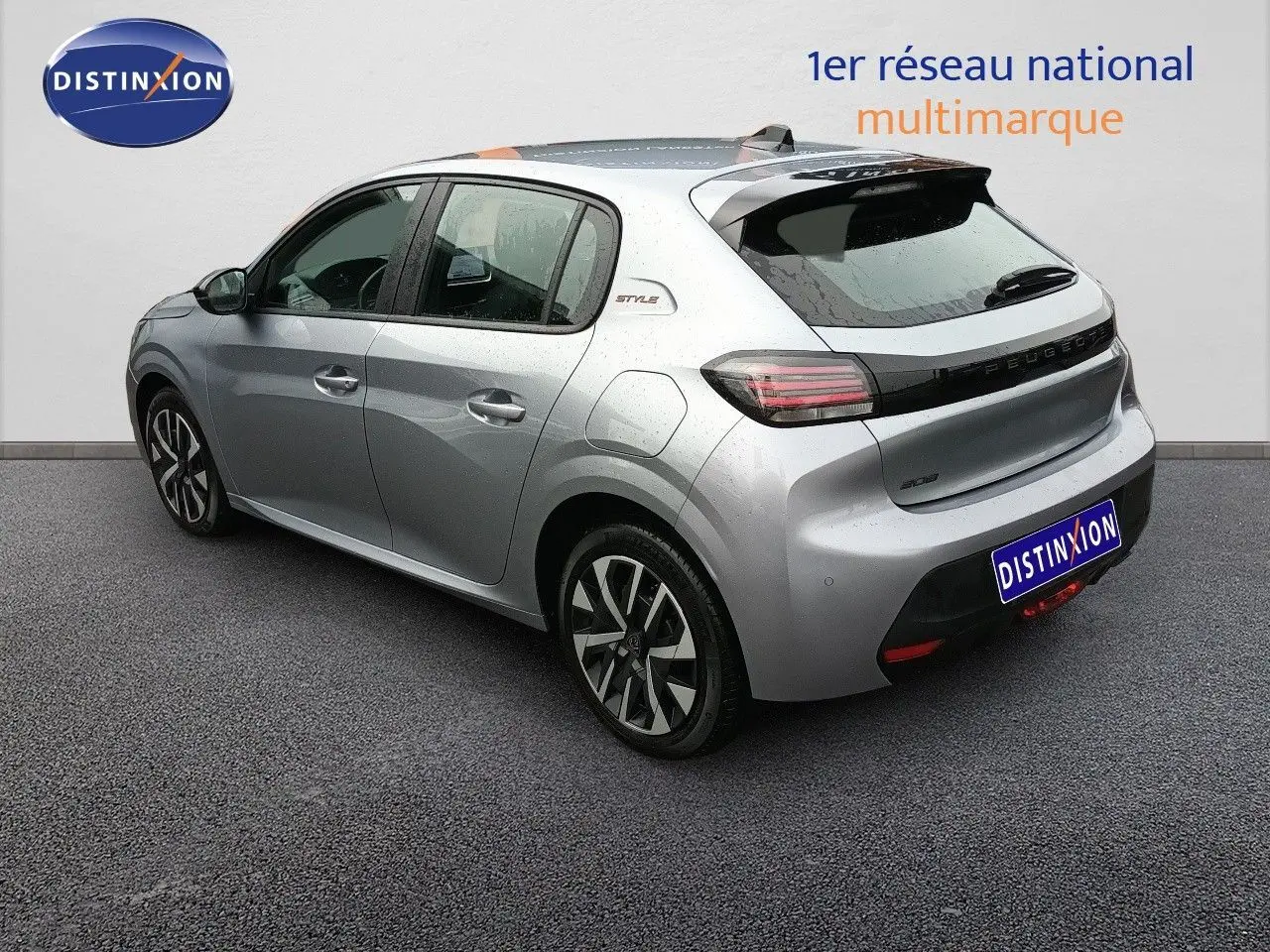 Vue 3/4 arrière droite d'une Peugeot 208 gris Artense métal avec jantes alliage et badge Style sur l'aile arrière.