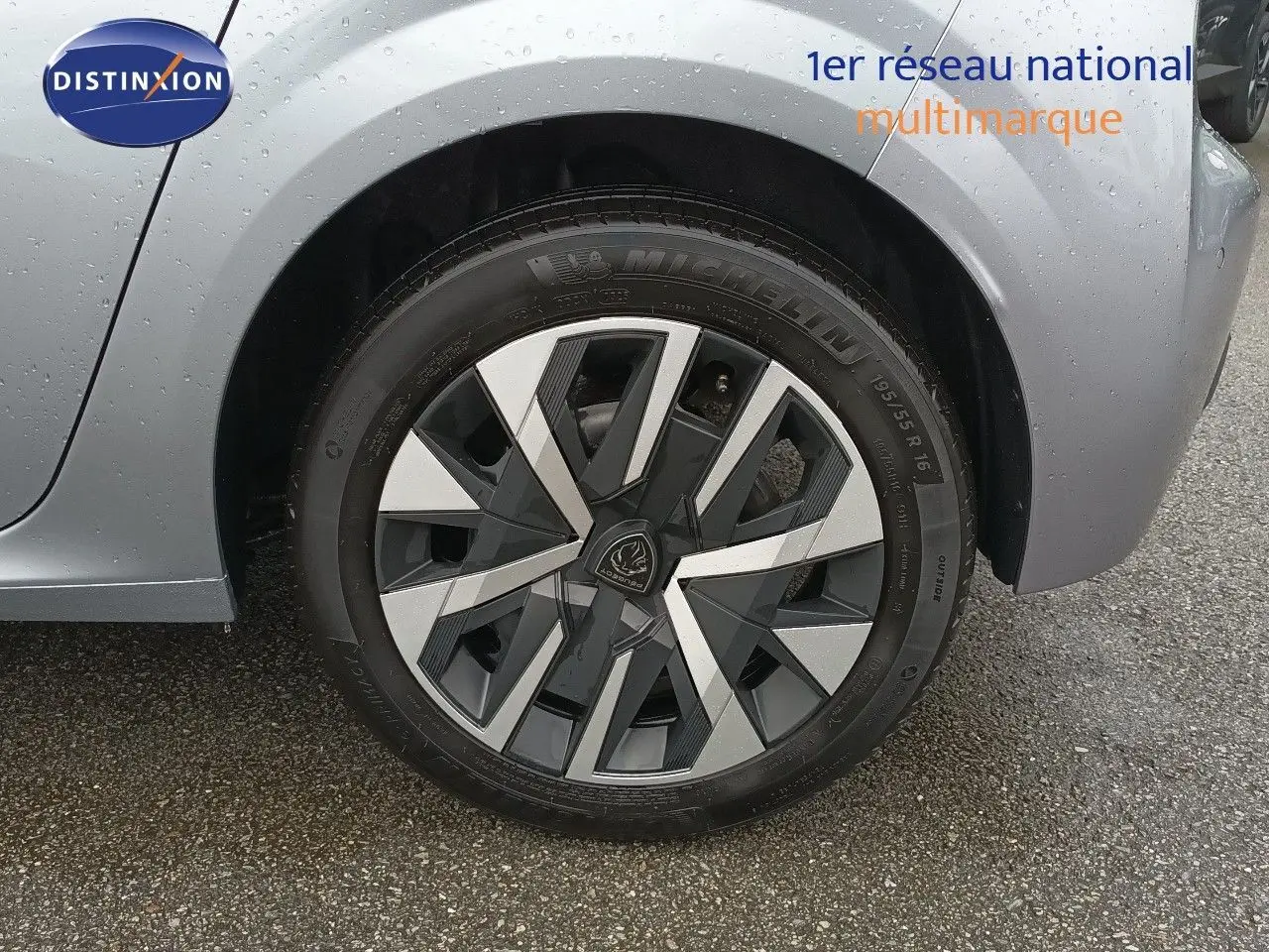 Gros plan sur la roue avant droite d’une Peugeot 208 gris Artense métal avec jante alliage au design géométrique.