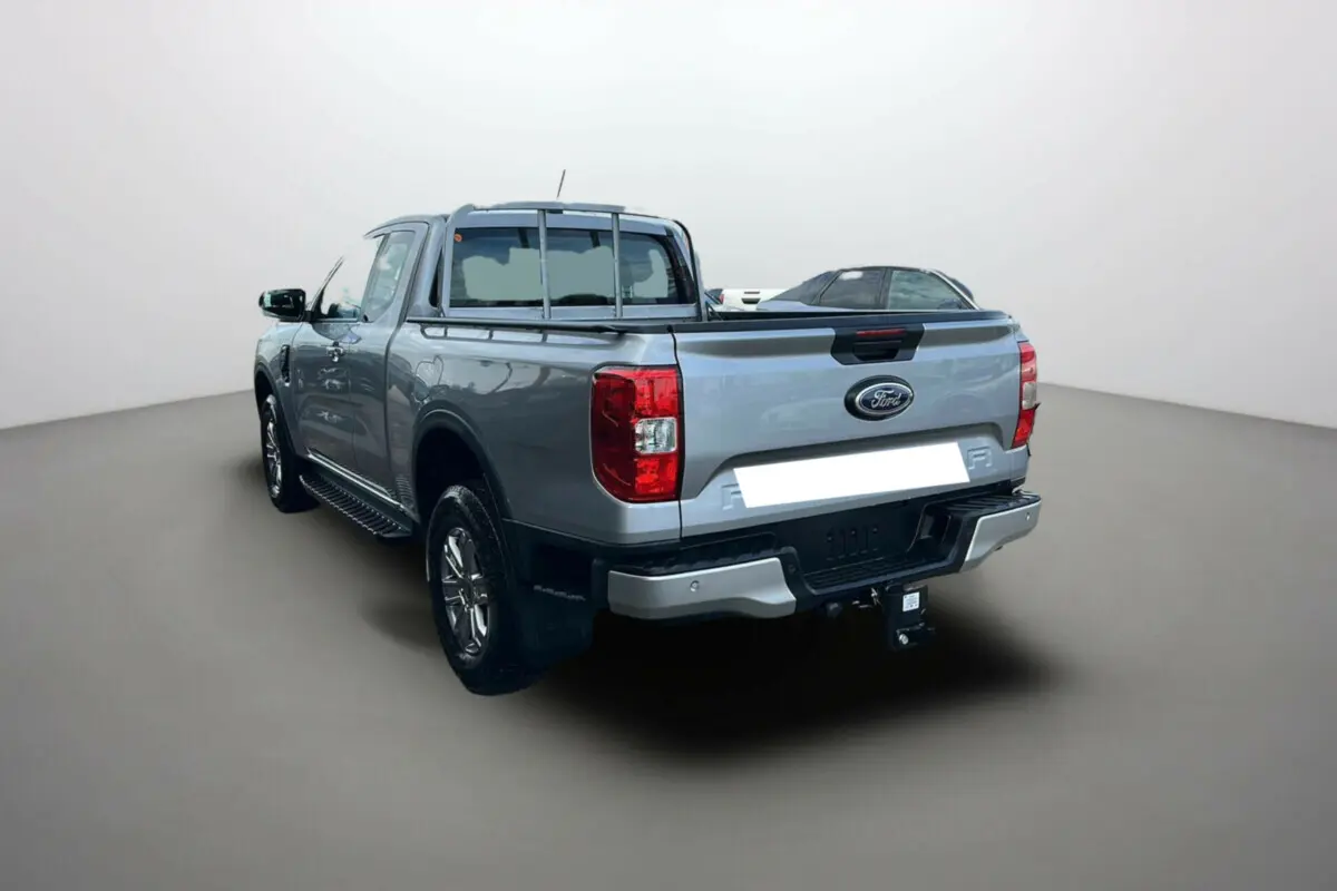 Vue 3/4 arrière gauche du Ford Ranger gris iconic avec attelage et marchepieds latéraux visibles.