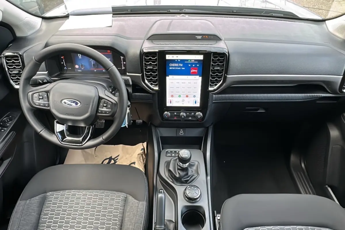 Vue intérieure frontale du Ford Ranger 2026 avec tableau de bord noir, écran tactile vertical et boîte manuelle.