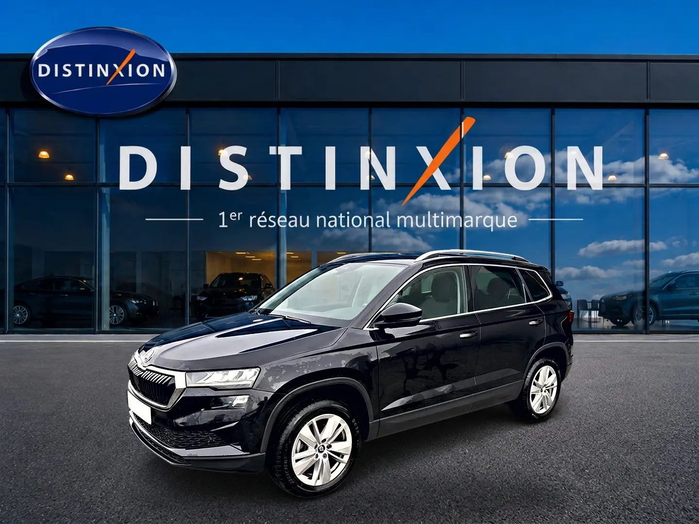 SKODA KAROQ noir 3/4 avant droit, jantes alu et barres de toit visibles devant vitrine Distinxion.