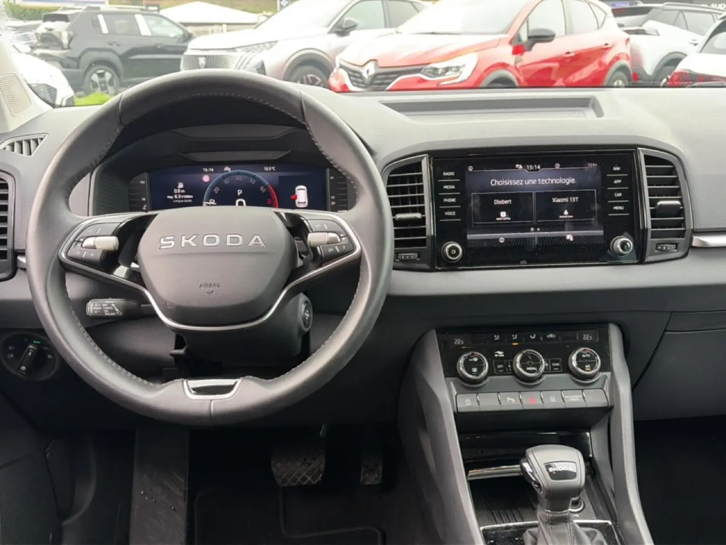 Vue intérieure frontale du tableau de bord et volant noir de la Skoda Karoq 1.5 TSI 2025 avec écran tactile et commandes au volant.