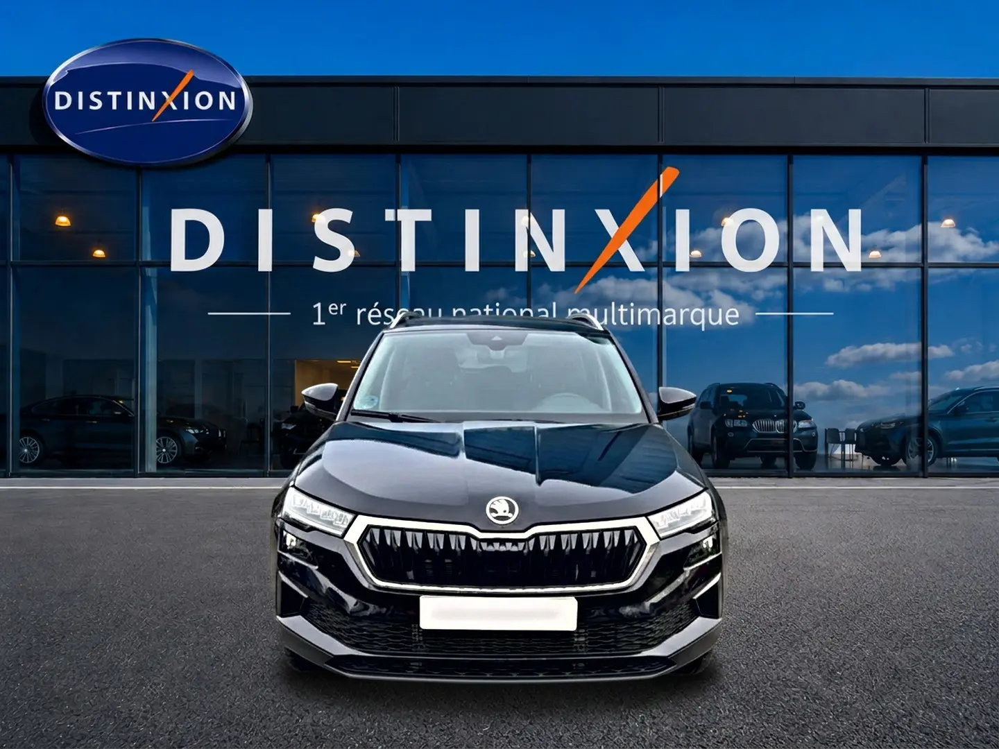 Vue avant d'un Skoda Karoq noir 2025 avec calandre chromée et phares LED devant une vitrine Distinxion.