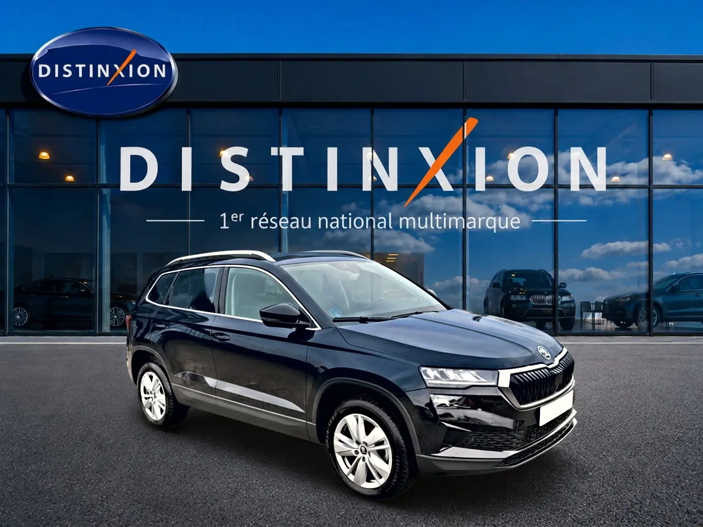 SUV Skoda Karoq noir en 3/4 avant droit, avec jantes alu, devant une vitrine Distinxion.