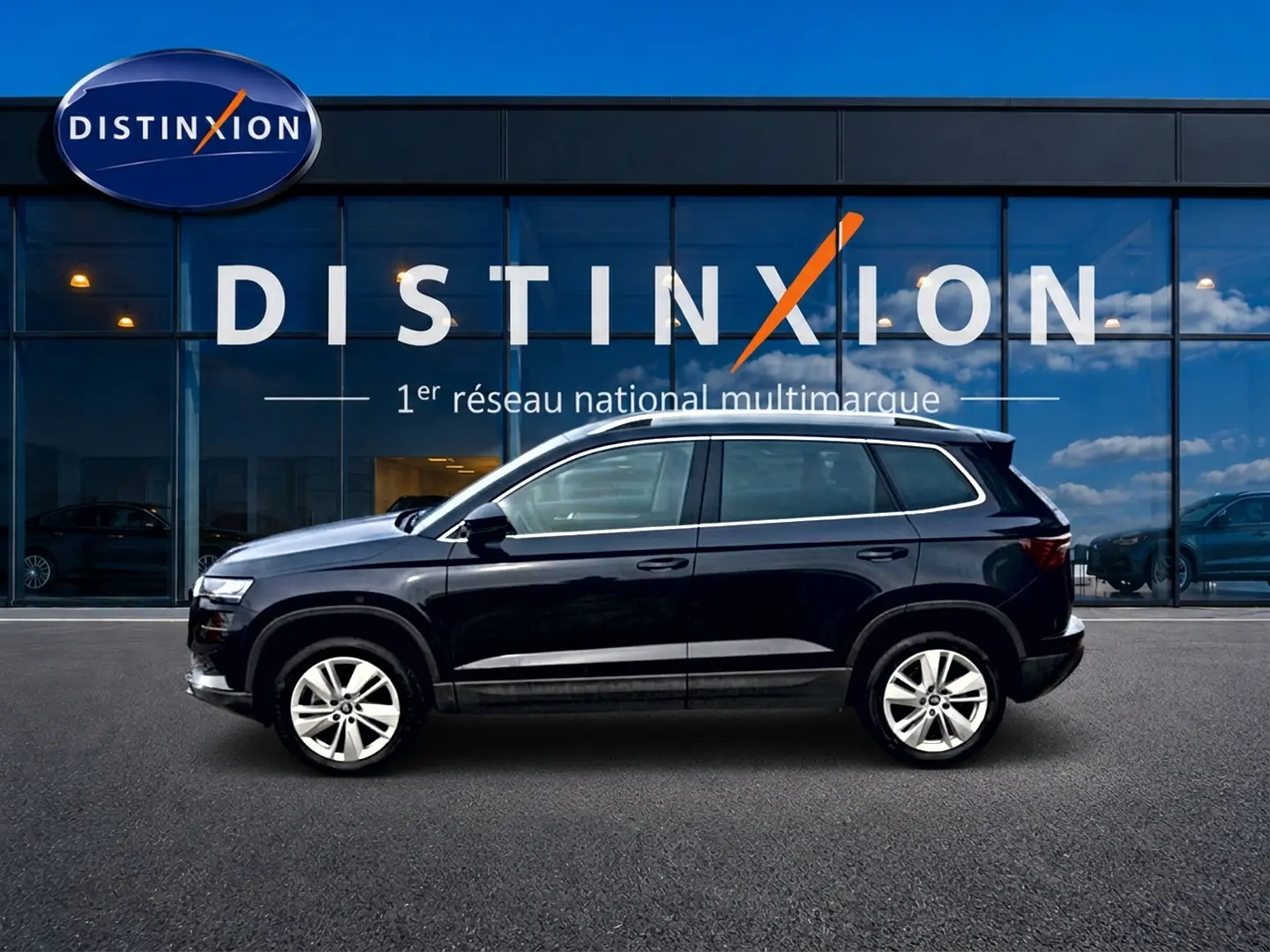 Vue latérale droite d'un Skoda Karoq noir 2025 avec jantes alu, devant une vitrine Distinxion.