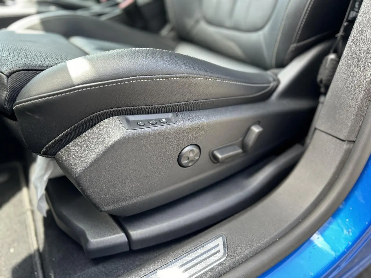 Gros plan sur le siège conducteur électrique en cuir noir avec réglages latéraux, intérieur d’un Opel Grandland Bleu Vertigo.