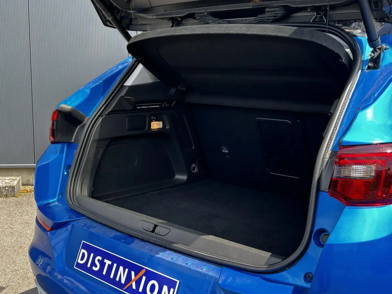 Coffre ouvert vu de l'arrière d'un Opel Grandland bleu Vertigo avec hayon électrique et feux arrière LED.