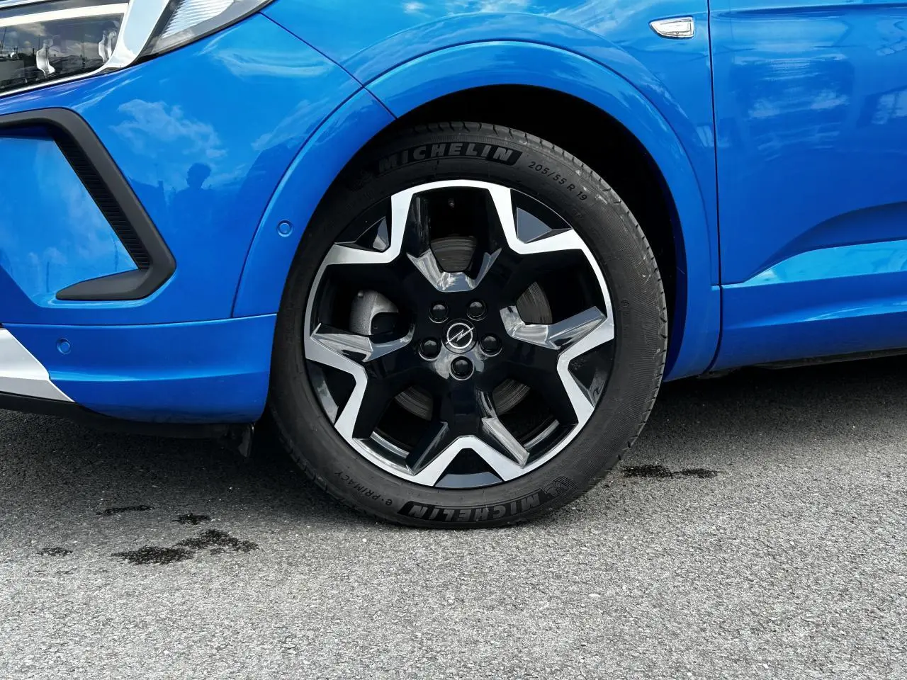 Gros plan sur la roue avant gauche de l'Opel Grandland bleu Vertigo avec jante alliage noire et argentée distinctive.