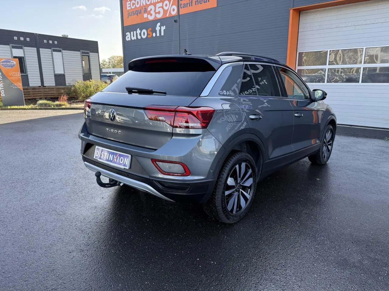 Vue 3/4 arrière droite du Volkswagen T-Roc gris Indium métallisé avec attelage amovible et jantes noires.