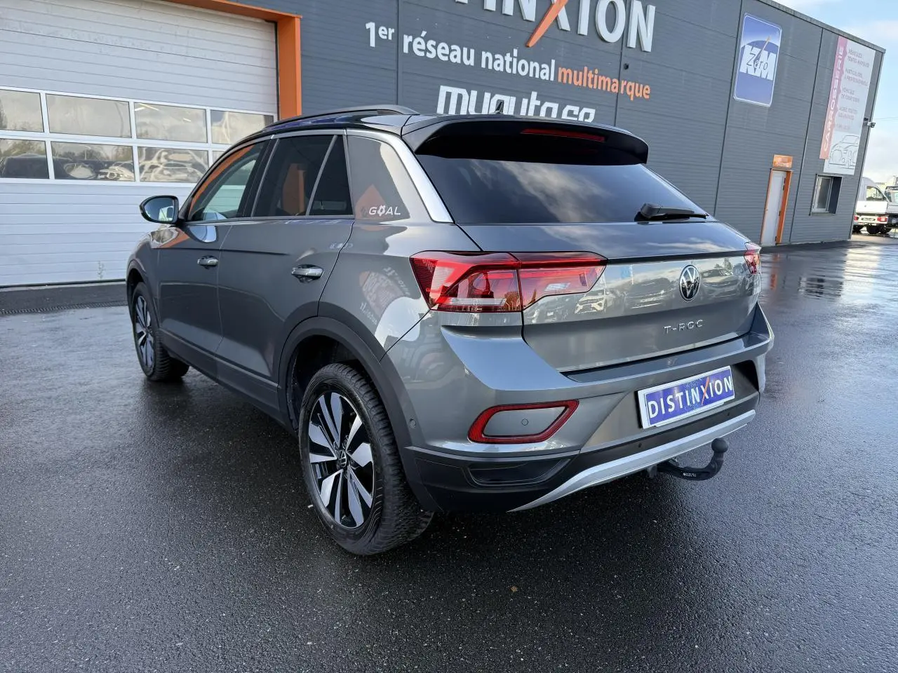 Volkswagen T-Roc gris Indium métallisé vu en 3/4 arrière droit avec attelage amovible et toit noir.