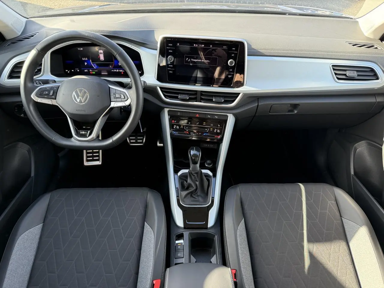 Vue intérieure frontale du tableau de bord et volant du Volkswagen T-Roc 2025 avec écran tactile et sellerie noire.