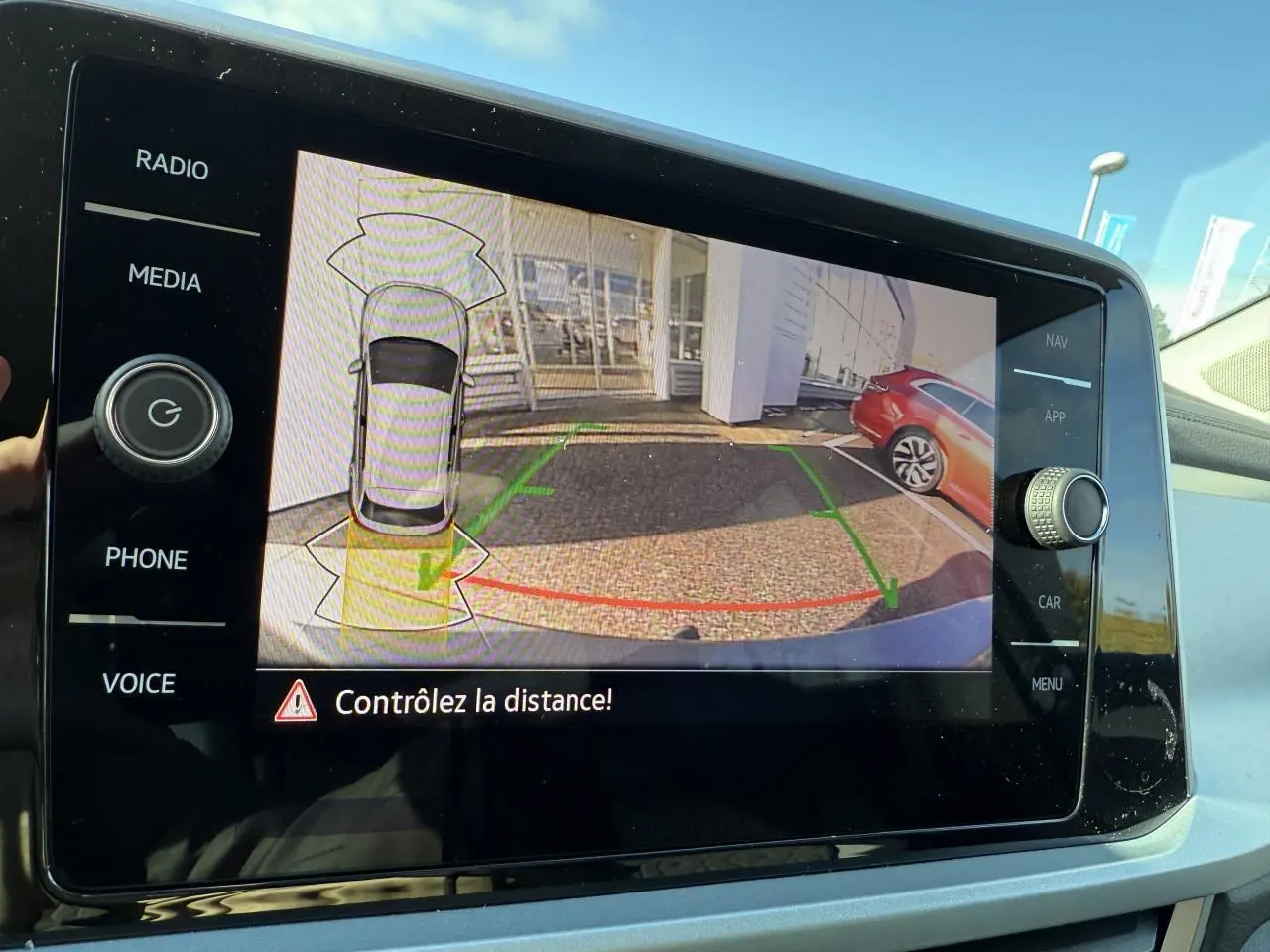 Écran tactile intérieur montrant la caméra de recul du Volkswagen T-Roc gris Indium métallisé en stationnement.