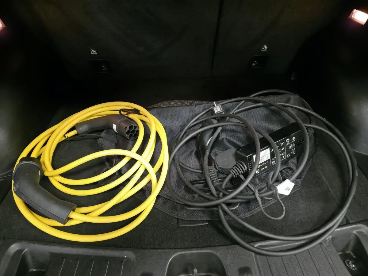 Câbles de recharge jaune et noir dans le coffre d'un Jeep Compass 2024 noir hybride rechargeable.