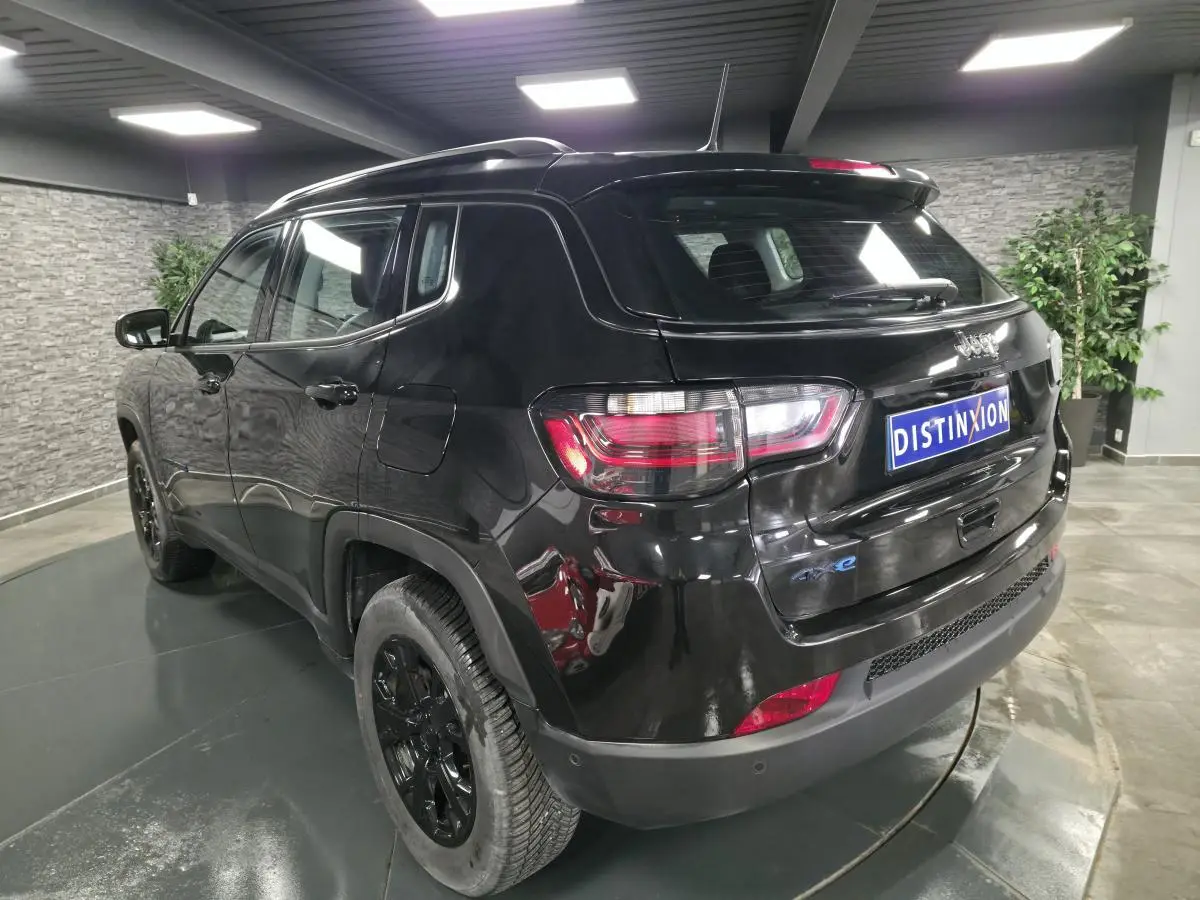 Vue 3/4 arrière droite du Jeep Compass noir brillant avec jantes noires et logo 4xe sur le hayon.
