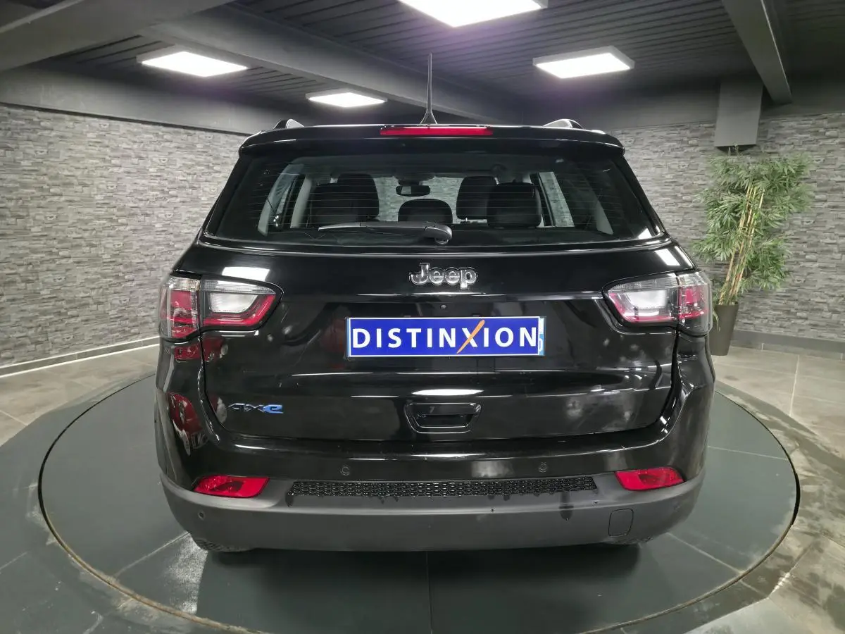 Vue arrière d'un Jeep Compass noir 2024 avec logo eAWD et plaque Distinxion dans un showroom moderne.