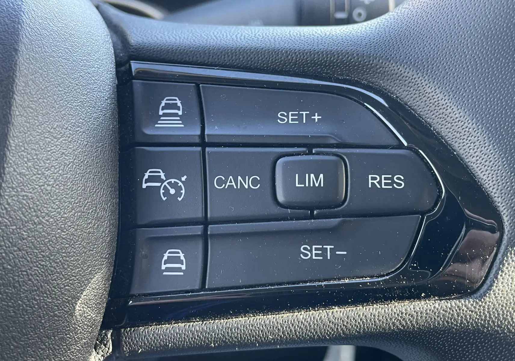 Gros plan sur les boutons de régulateur et limiteur de vitesse sur le volant du Peugeot Boxer Fourgon blanc.