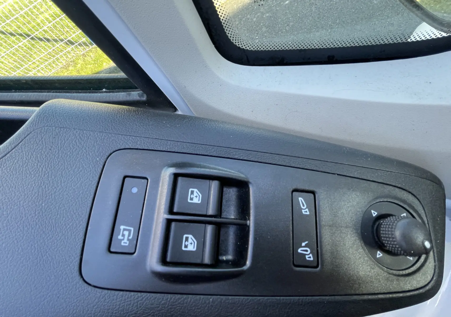 Gros plan sur les commandes de lève-vitres et réglage des rétroviseurs côté conducteur du Peugeot Boxer Fourgon blanc.