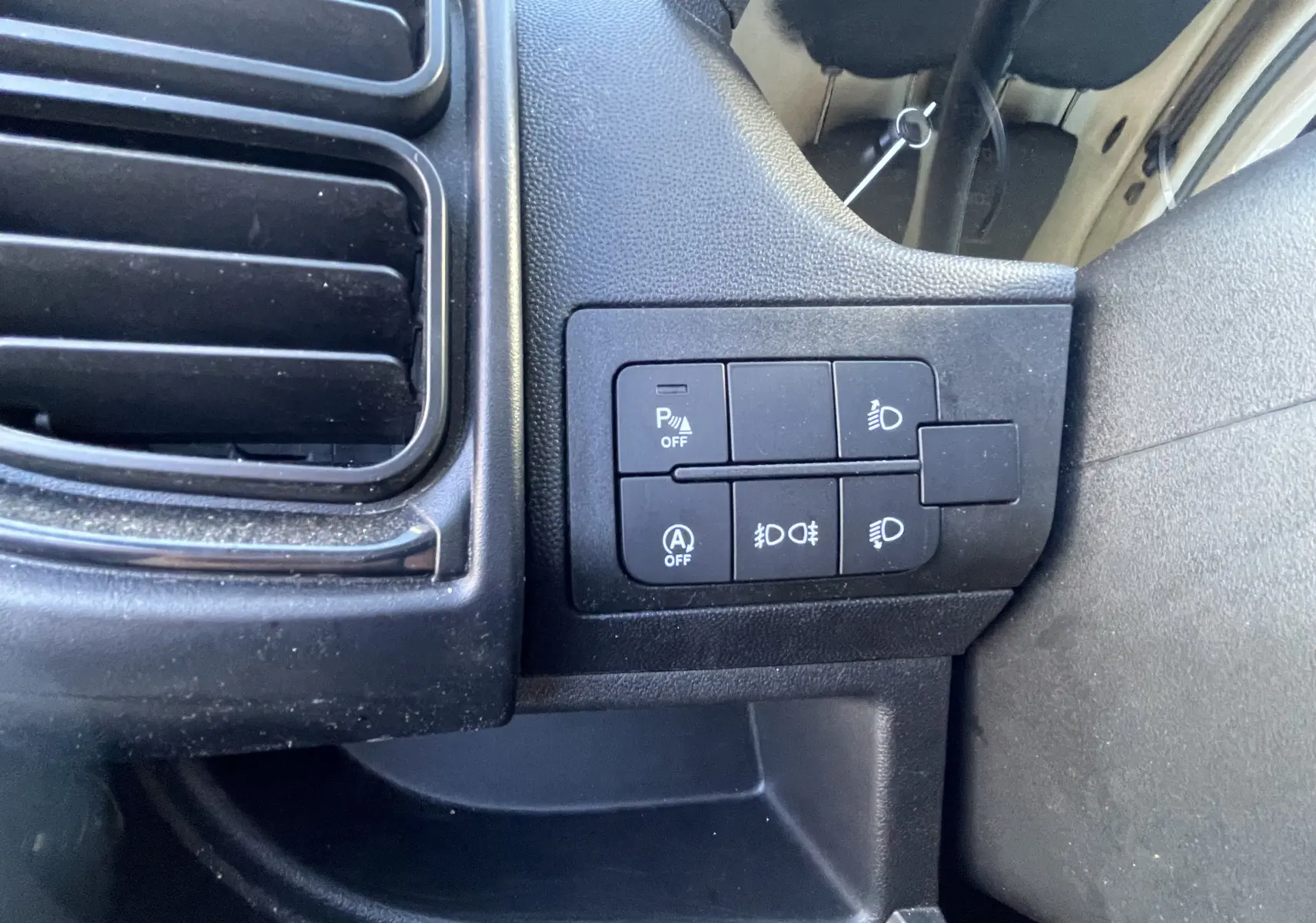 Gros plan sur les commandes de réglage des phares et aides à la conduite du Peugeot Boxer Fourgon blanc, intérieur côté conducteur.