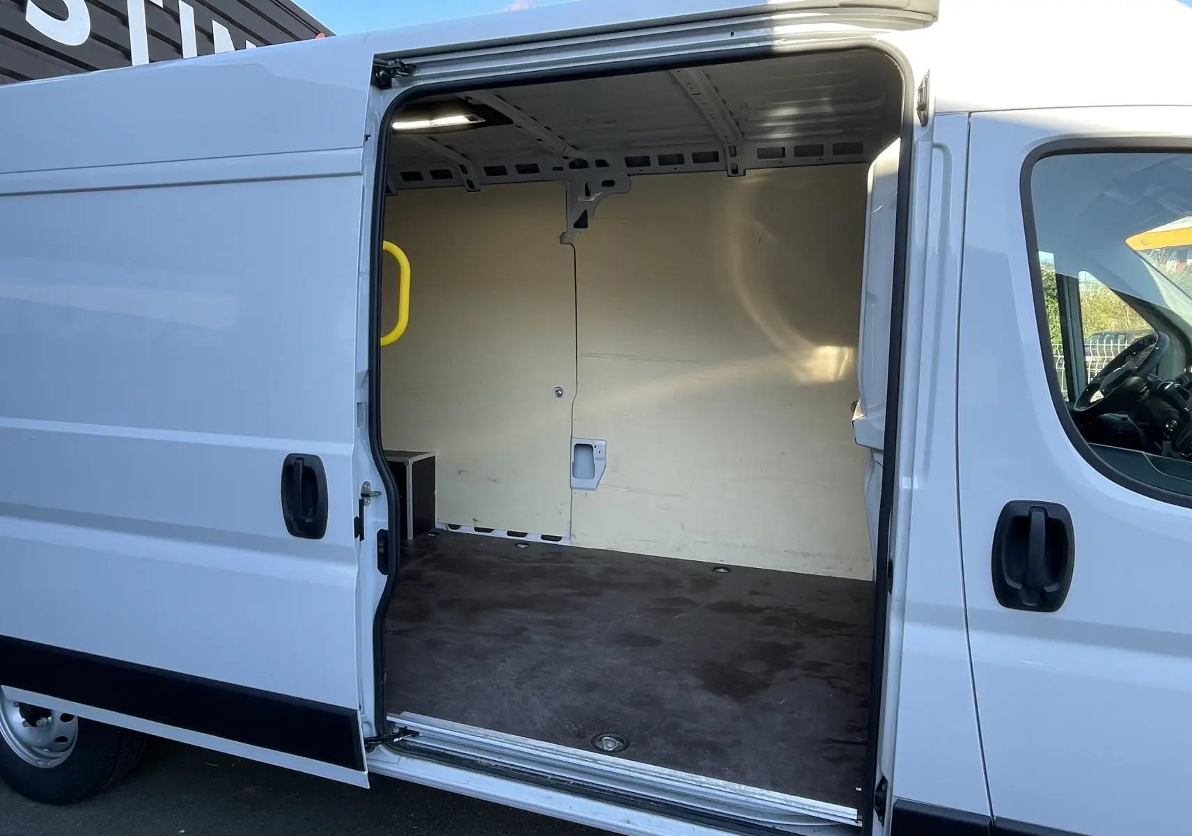Vue latérale droite d’un Peugeot Boxer Fourgon blanc 2025 avec porte coulissante ouverte montrant l’espace de chargement vide.