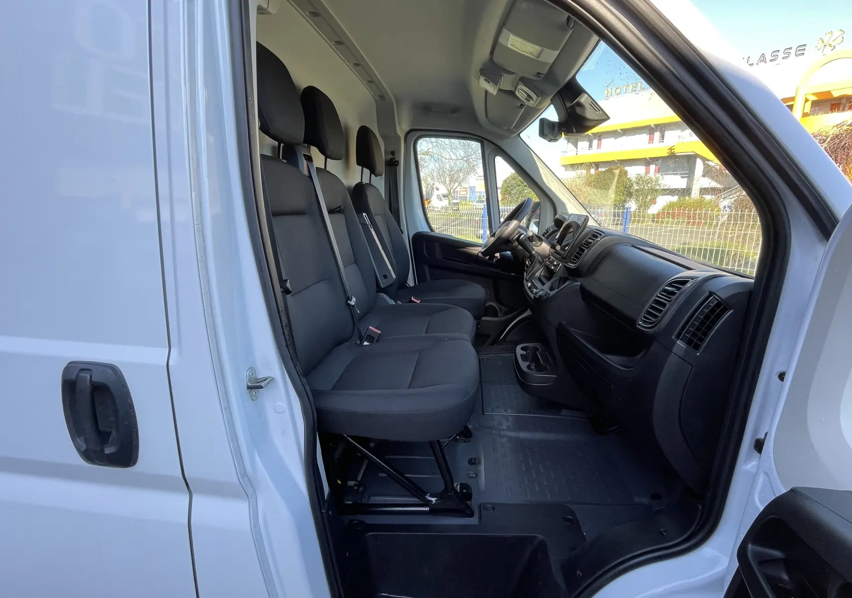 Vue intérieure côté droit du Peugeot Boxer Fourgon blanc 2025, montrant les trois sièges avant et le tableau de bord.
