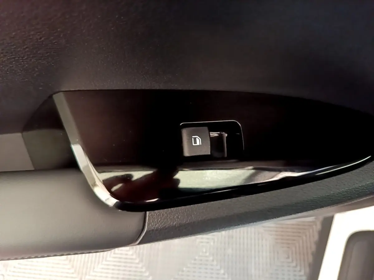 Gros plan sur le bouton de verrouillage des portes côté conducteur du Kia Sportage blanc, intérieur noir.