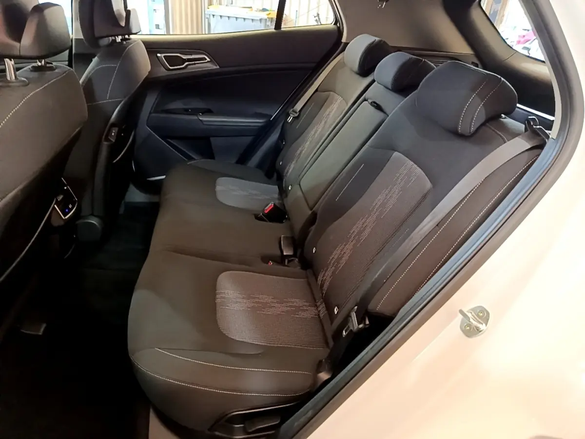 Vue intérieure côté droit sur la banquette arrière noire du Kia Sportage blanc, avec appuie-têtes et ceintures visibles.