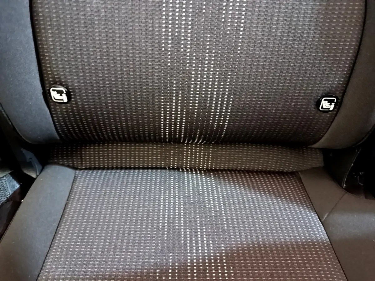 Gros plan sur la banquette arrière en tissu gris foncé avec motifs clairs et fixations Isofix visibles sur une KIA SPORTAGE blanche.