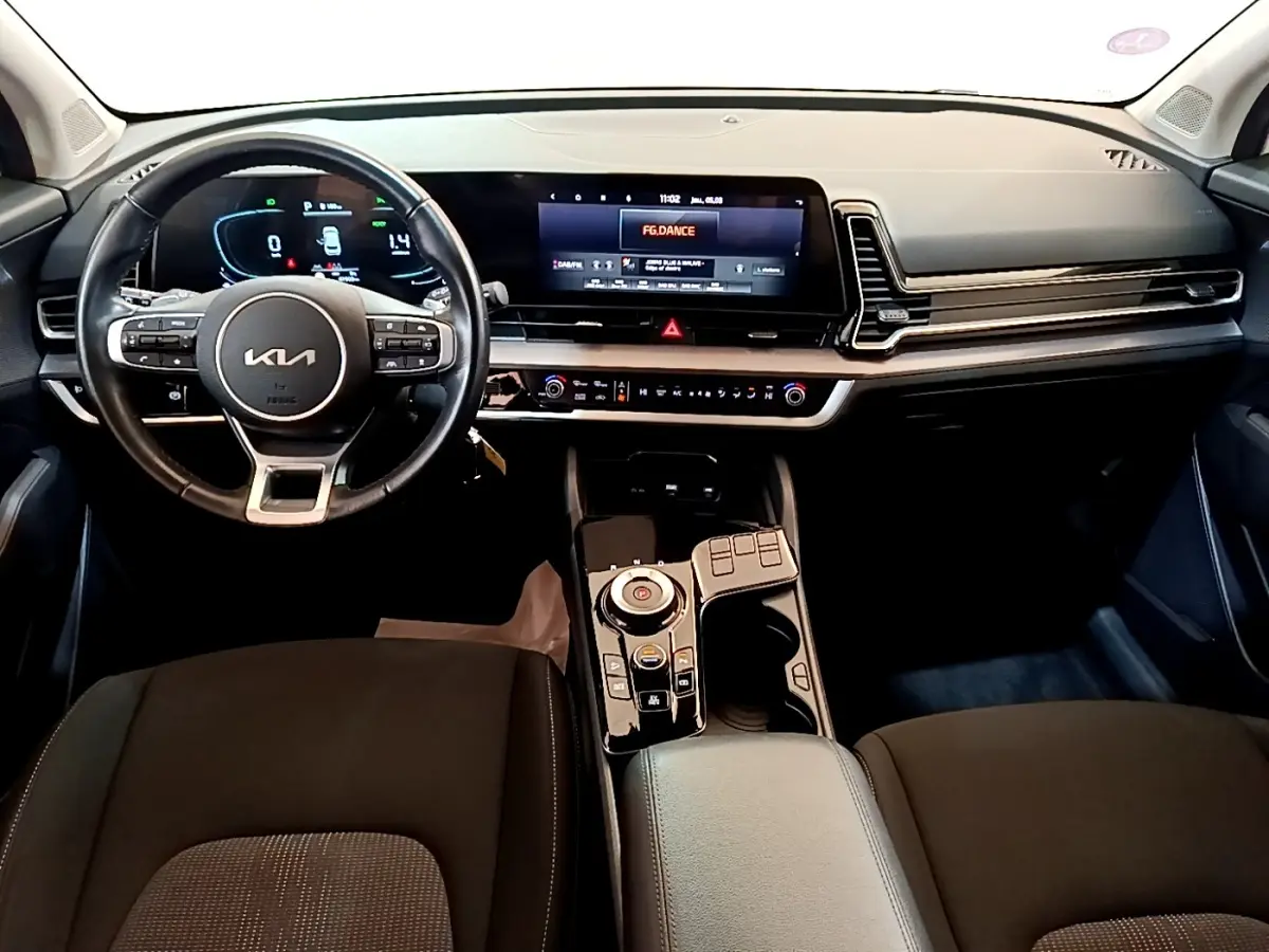Vue intérieure avant du tableau de bord du Kia Sportage 2022, avec volant cuir et écran tactile large noir.