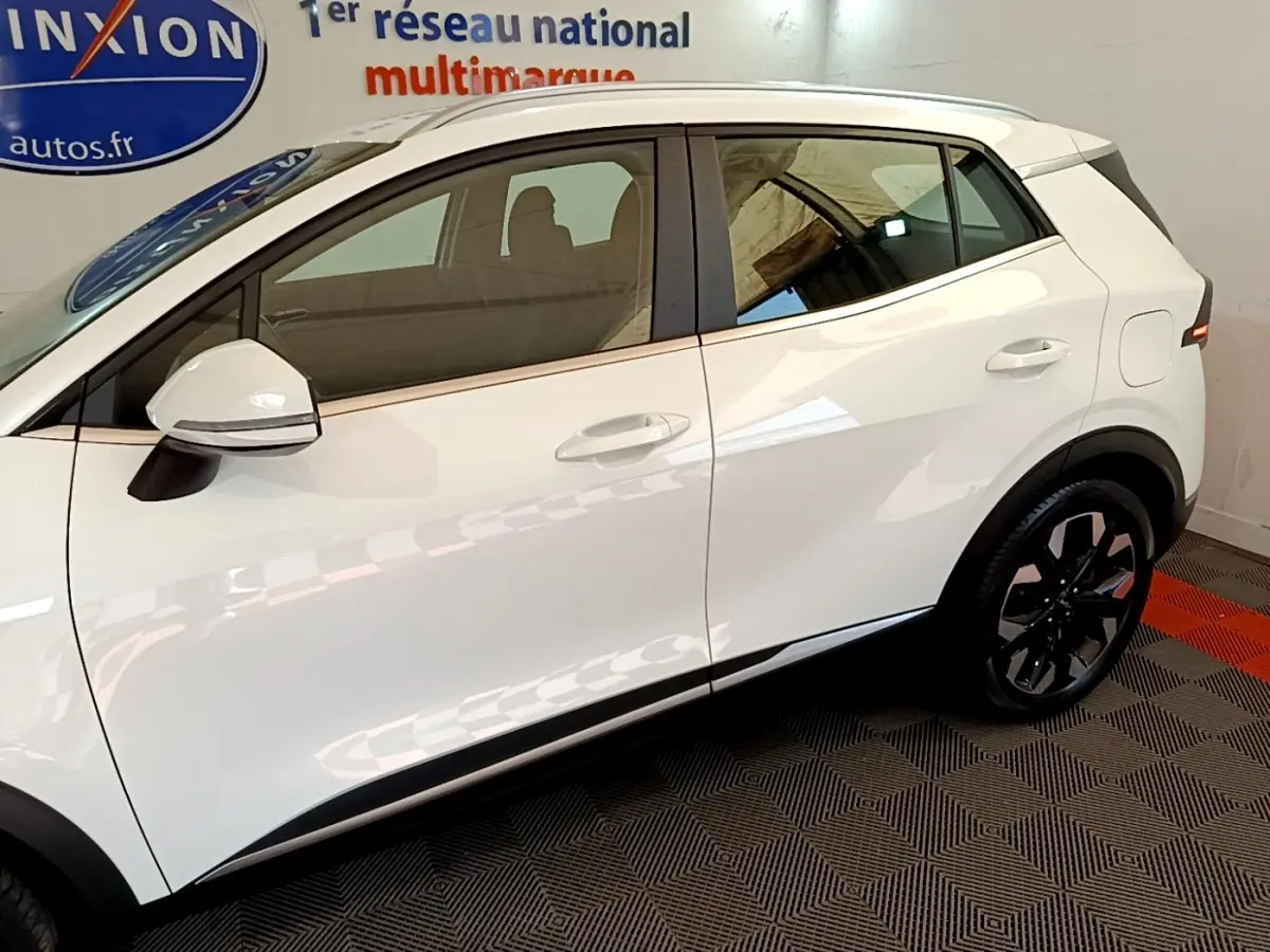 Profil droit du KIA SPORTAGE blanc 2022 hybride rechargeable, avec rétroviseur et jante noire au design moderne.