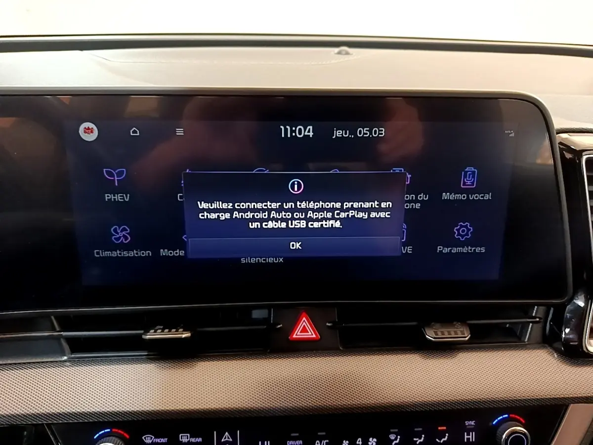 Gros plan sur l'écran tactile central du tableau de bord du Kia Sportage blanc, affichant un message de connexion USB.