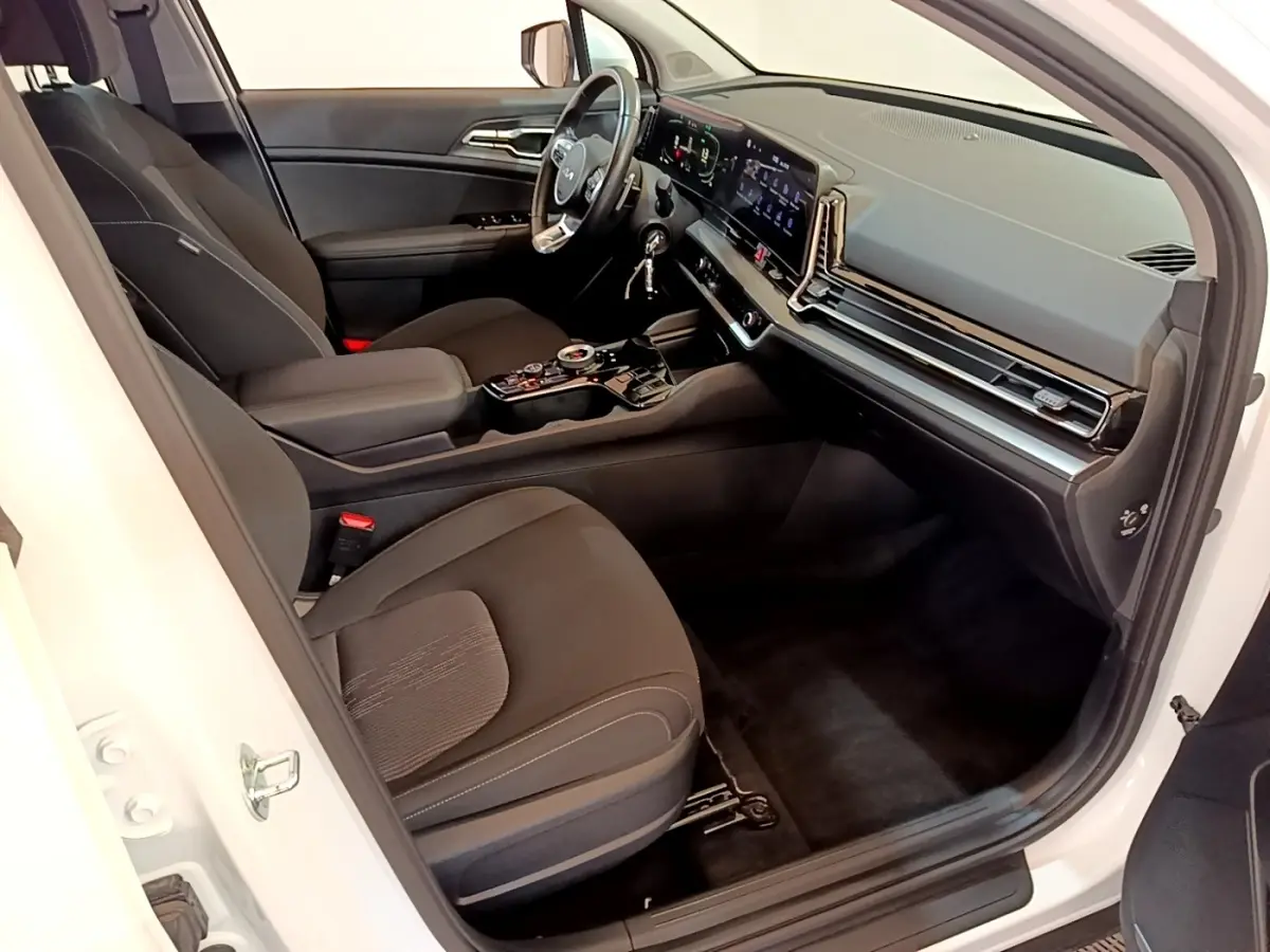 Vue intérieure côté conducteur du Kia Sportage blanc 2022, avec tableau de bord numérique et sièges noirs.