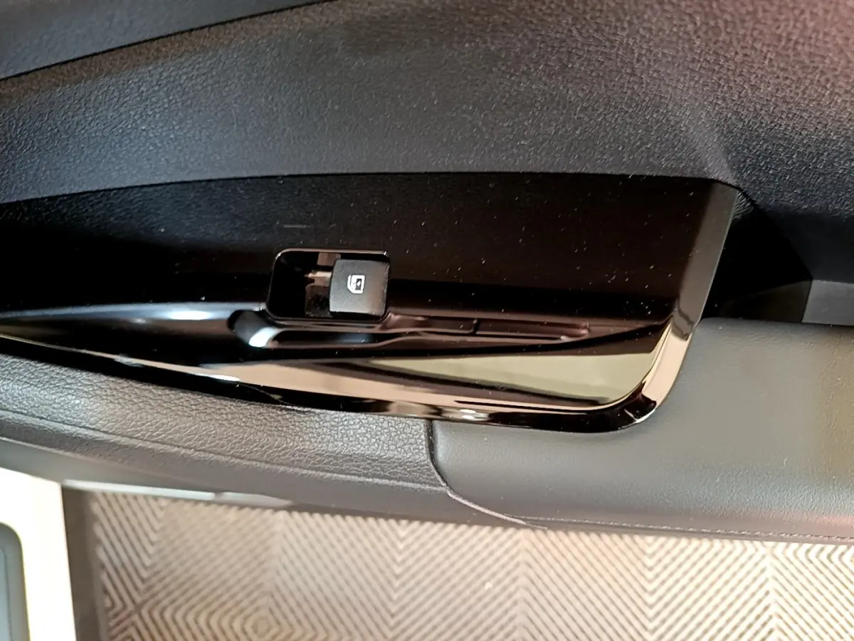 Gros plan sur le bouton de verrouillage des vitres côté conducteur du KIA Sportage blanc 2022.