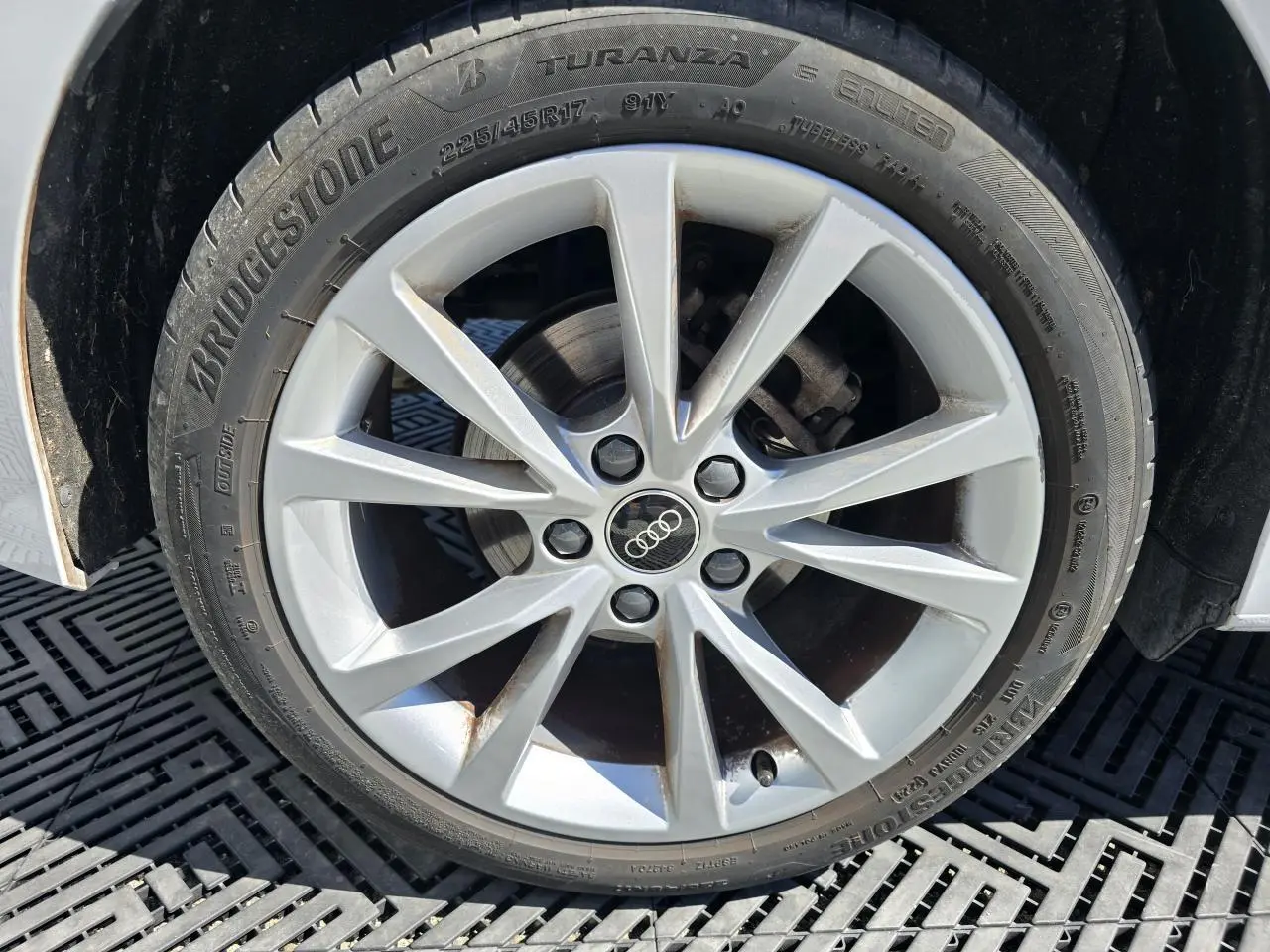 Gros plan sur la jante alliage 5 branches parallèles de l'Audi A3 Sportback blanc Arkona, pneu Bridgestone visible.