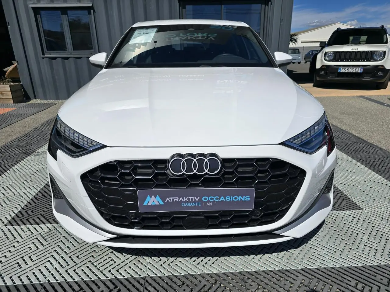 Audi A3 Sportback blanc Arkona vue de face mettant en valeur la calandre noire hexagonale et les phares LED distinctifs.