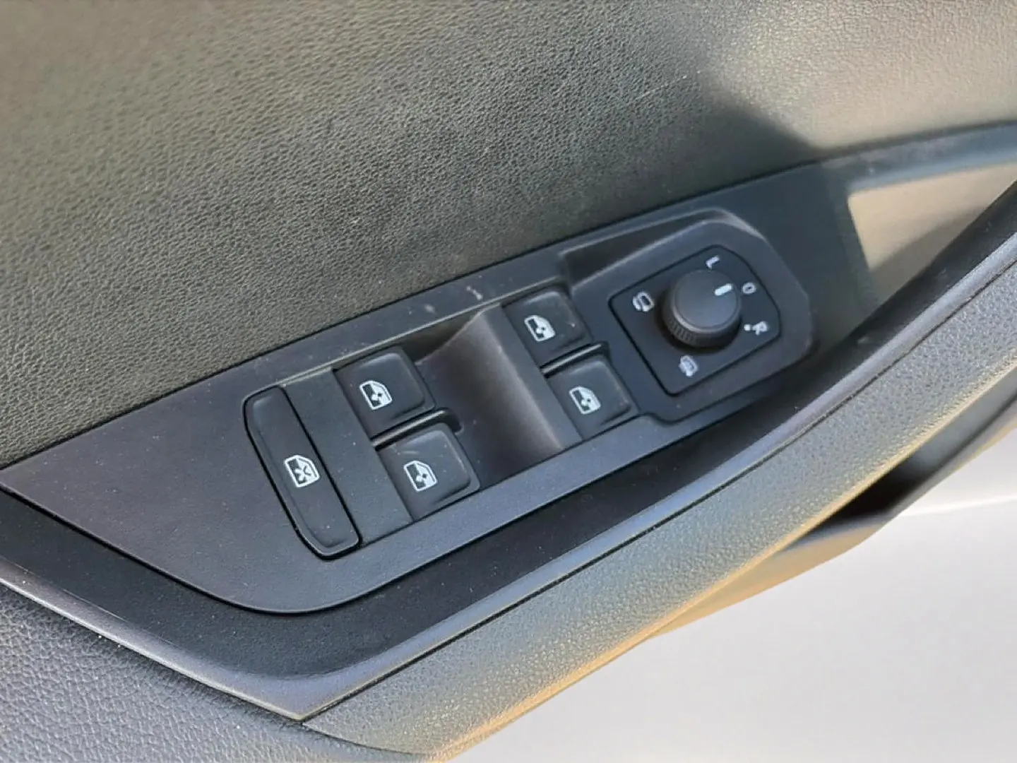 Gros plan sur les commandes des vitres et rétroviseurs côté conducteur d’un Skoda Karoq gris 2025.