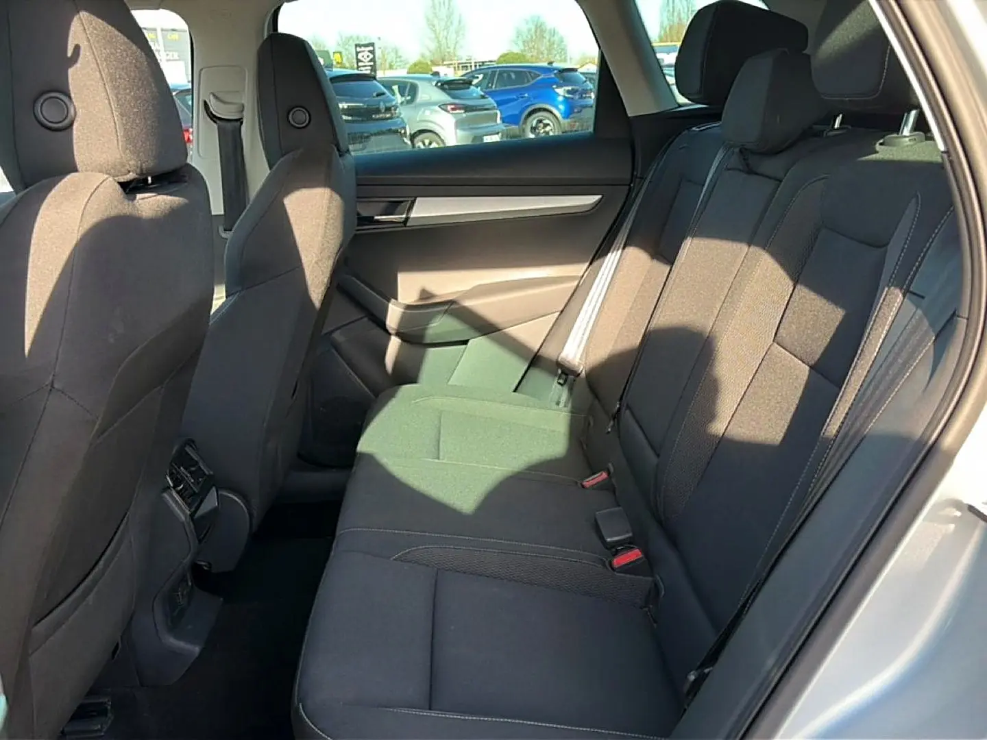 Vue intérieure côté droit des sièges arrière noirs du Skoda Karoq gris 2025 avec porte ouverte et lumière naturelle.